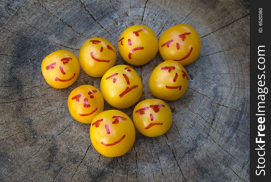 Yellow plums painted as emoticons on wood surface in backyard. Yellow plums painted as emoticons on wood surface in backyard