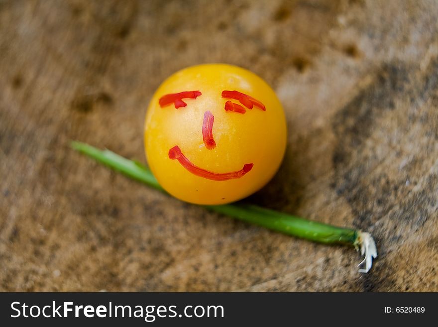 Yellow little plum with face design with stik on wood surface. Yellow little plum with face design with stik on wood surface