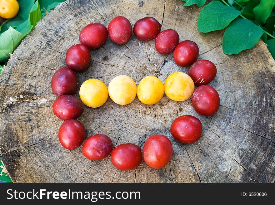 Red and yellow plums in form of traffic sign on wood surface. Red and yellow plums in form of traffic sign on wood surface