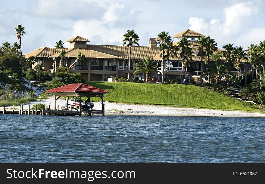 Beach home on a tropical island surrounded by water, a boat dock, a sandy beach and  a motor boat.