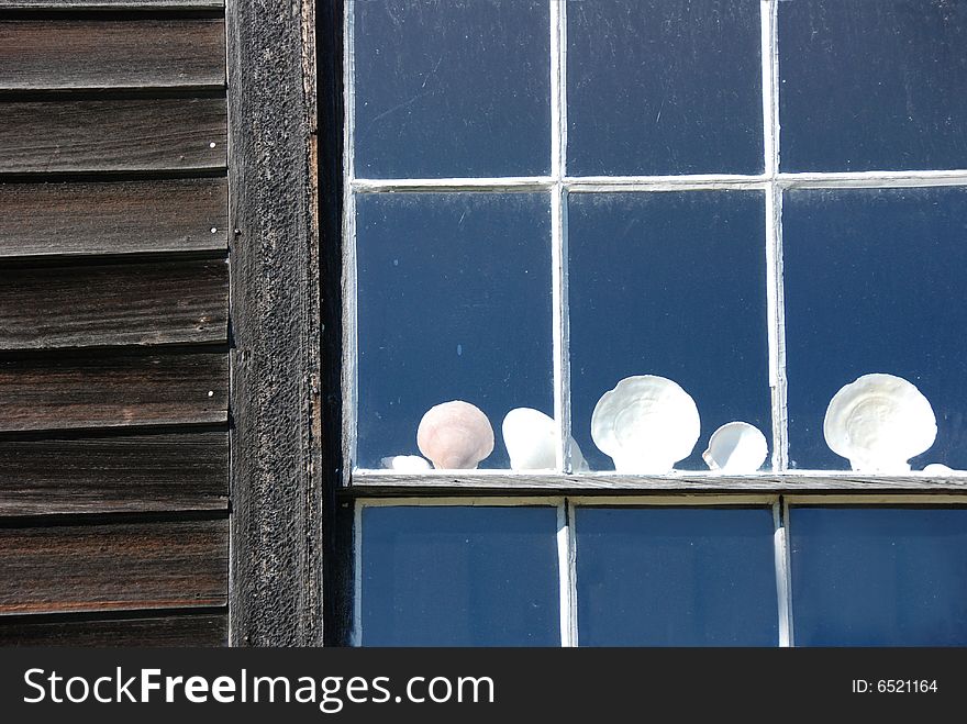 An array of shells line the window of an old home or barn. An array of shells line the window of an old home or barn.