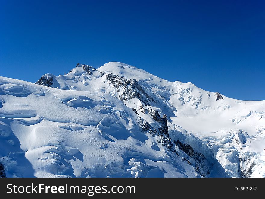 Blue sky above peaks and glacier, the Alps