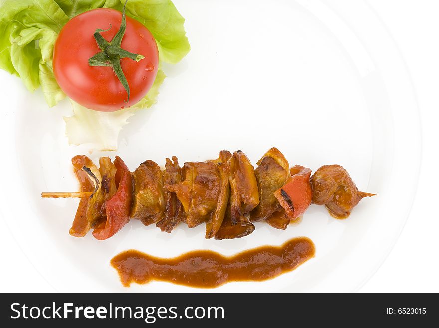 Shashlik on a plate with a tomato and salad leaf