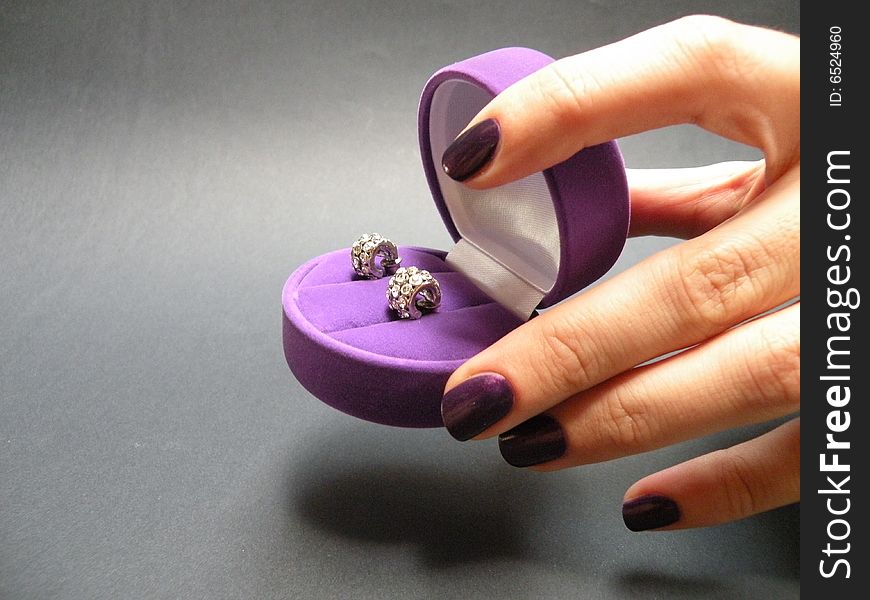 Hand holding purple velvet box for ear-rings
