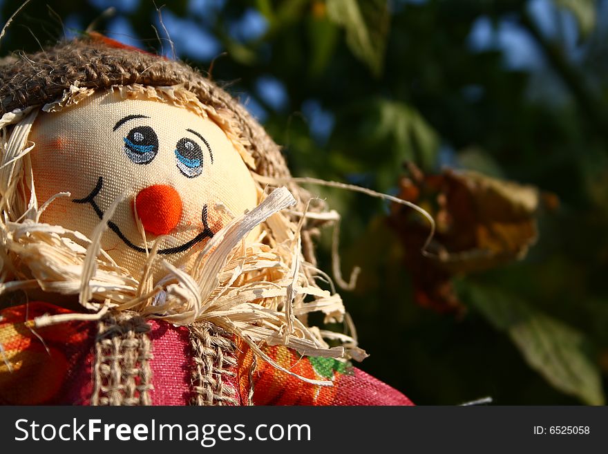 A smiling festive scarecrow made of straw.