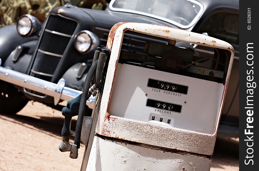 A vintage car awaits a vintage gas pump. A vintage car awaits a vintage gas pump