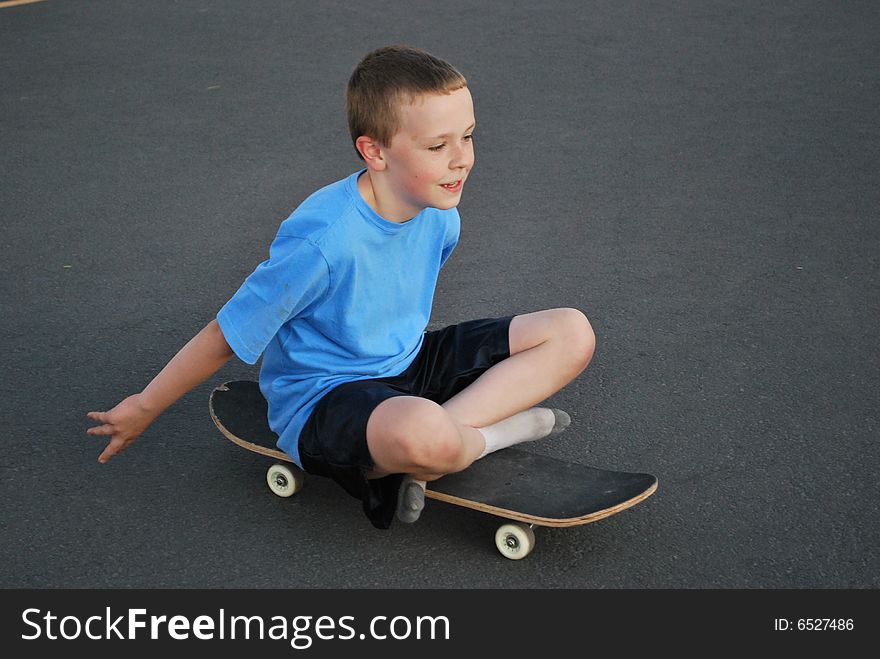 Young boy being silly sitting on skateboard. Young boy being silly sitting on skateboard.