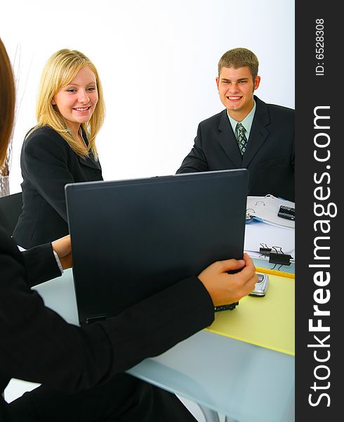 Two caucasian business people, man and woman, looking at laptop presented by other businesswoman. concept for teamwork. Two caucasian business people, man and woman, looking at laptop presented by other businesswoman. concept for teamwork