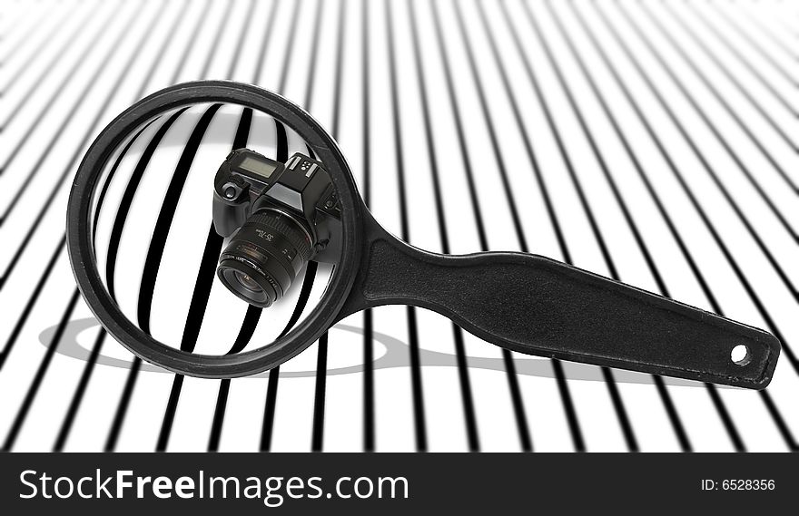 Black camera on a striped background, visible through a magnifier