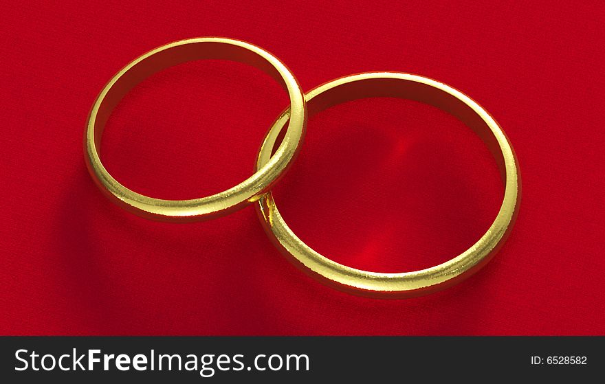 Hammered gold wedding rings on red silk background.