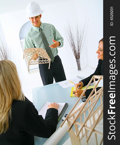 Happy caucasian contractor showing house model to two businesswoman. concept for architecture and construction. Happy caucasian contractor showing house model to two businesswoman. concept for architecture and construction