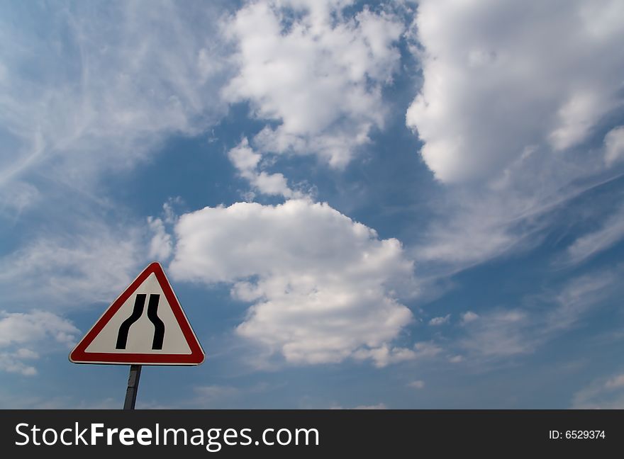 Sign Narrowing a road on background of cloudy sky