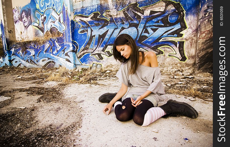 Rebel young girl sitting in a dirty place.