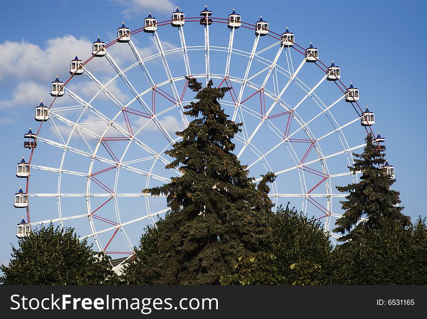 Ferris wheel at trees and blue sky