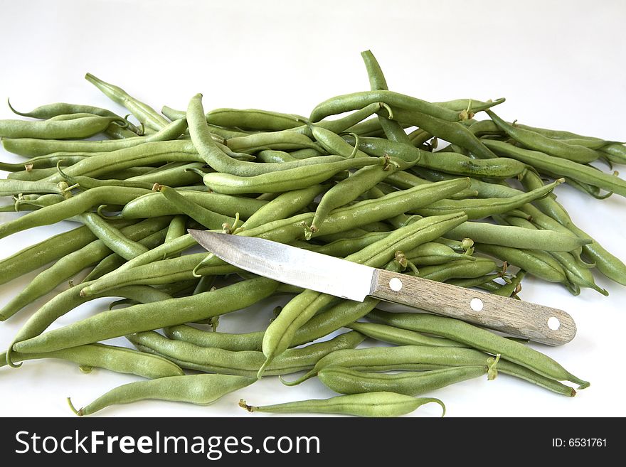 Pile of green bush beans with small vegetable knife on white background. Pile of green bush beans with small vegetable knife on white background.