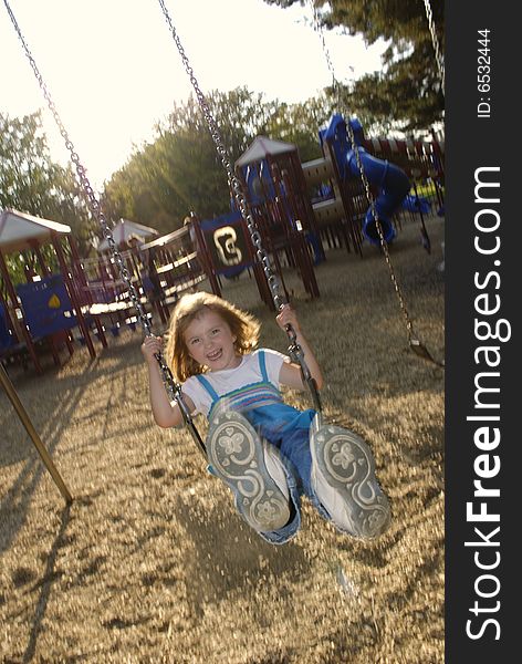 Little girl playing on swing set at a park. Little girl playing on swing set at a park