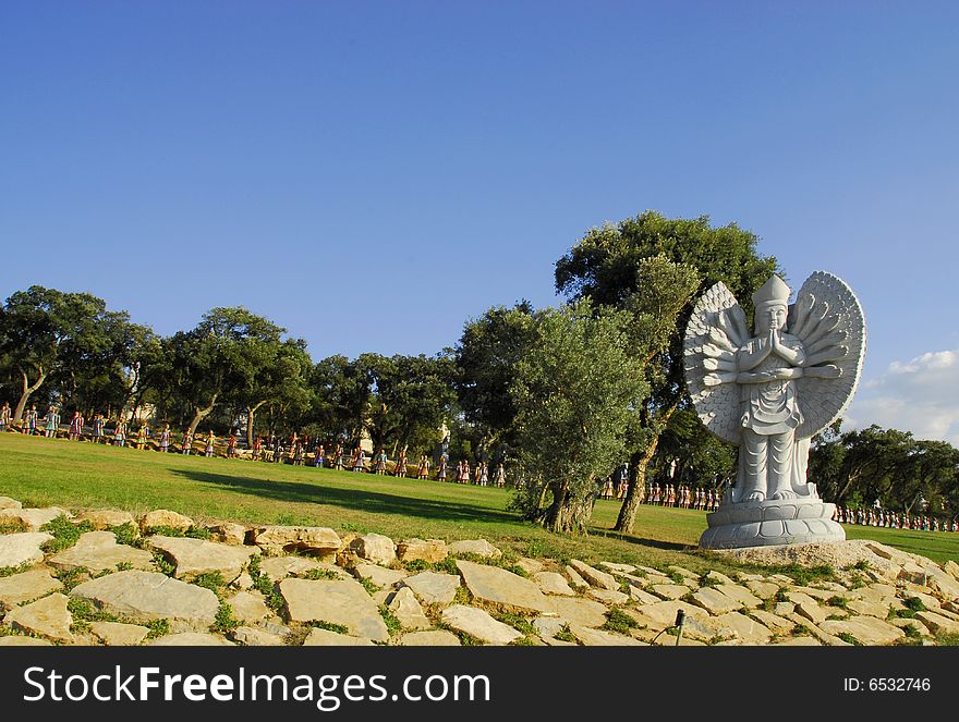 Buddha in the eastern garden with the soldiers in the background, in Qta. Of Loridos, Bombarral, Portugal. Buddha in the eastern garden with the soldiers in the background, in Qta. Of Loridos, Bombarral, Portugal