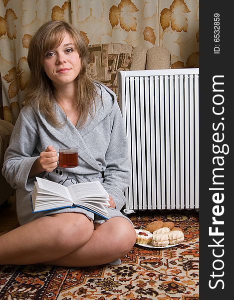 Pretty woman sits on a carpet with tea cup