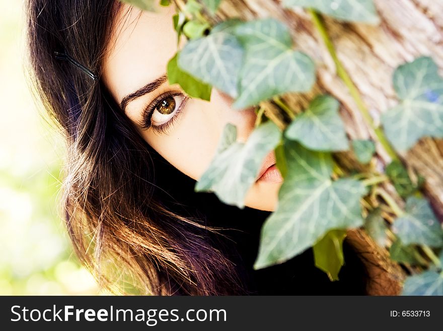Young beautiful woman observing behind leaves. Young beautiful woman observing behind leaves.