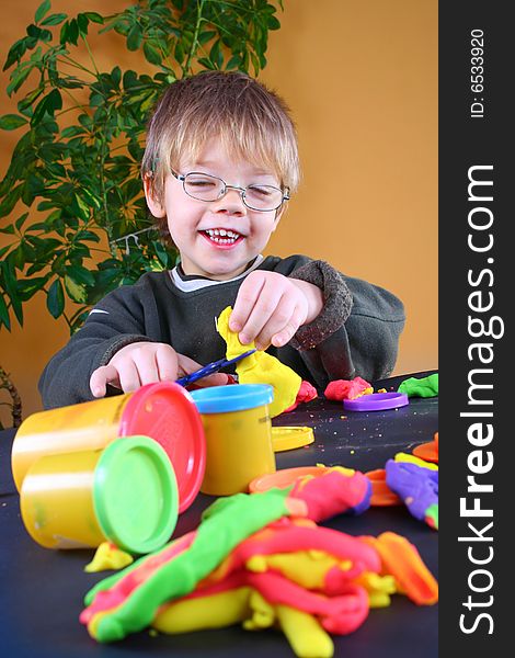 Young cute boy playing with plasticine. Young cute boy playing with plasticine