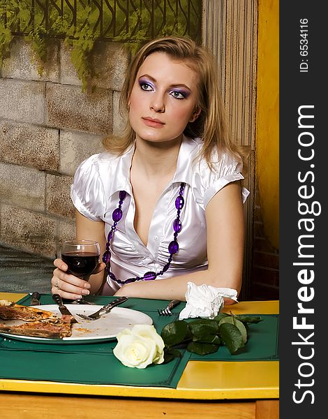 Young woman on dinner in pizzeria with glass of wine in hand.
