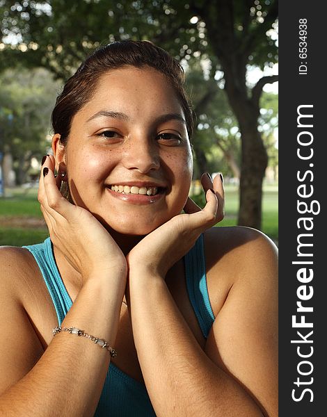 Young woman smiling with her hands under her face. Young woman smiling with her hands under her face