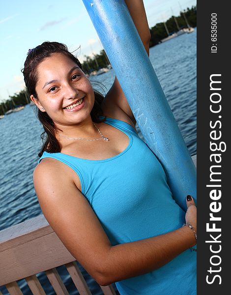 Young female on a pier holding on to a pole. Young female on a pier holding on to a pole