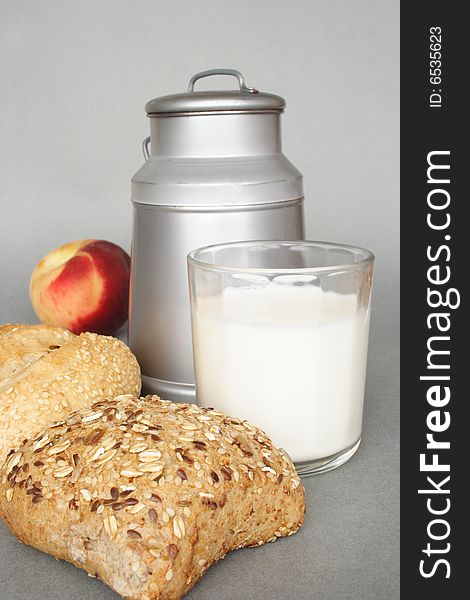 Can and glass of milk with seed bread and fruit. Can and glass of milk with seed bread and fruit