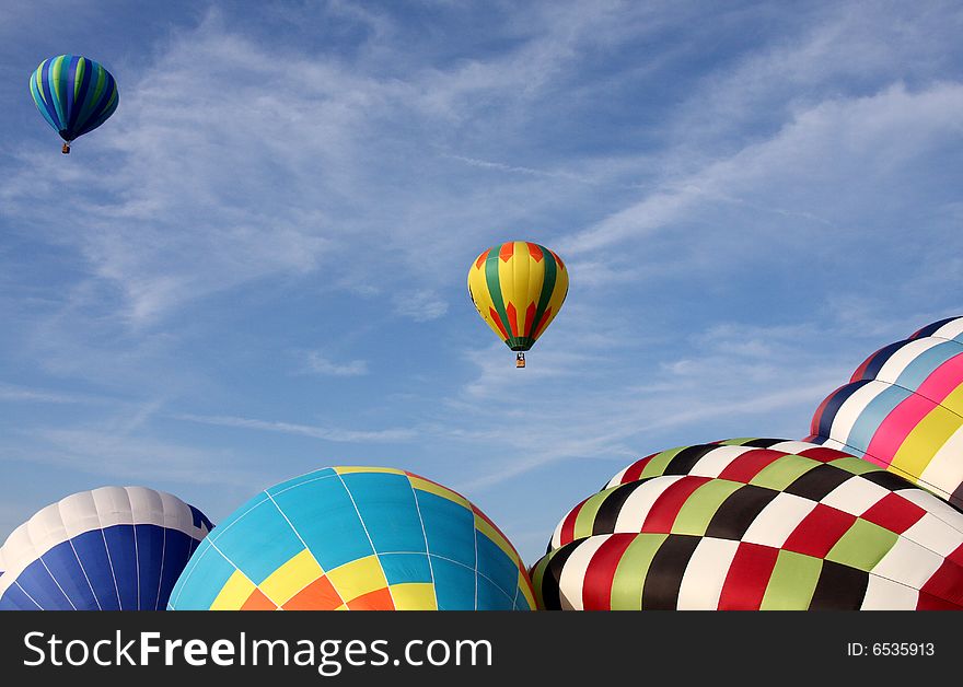 Multi-colored hot air balloons ascending into the clear blue sky