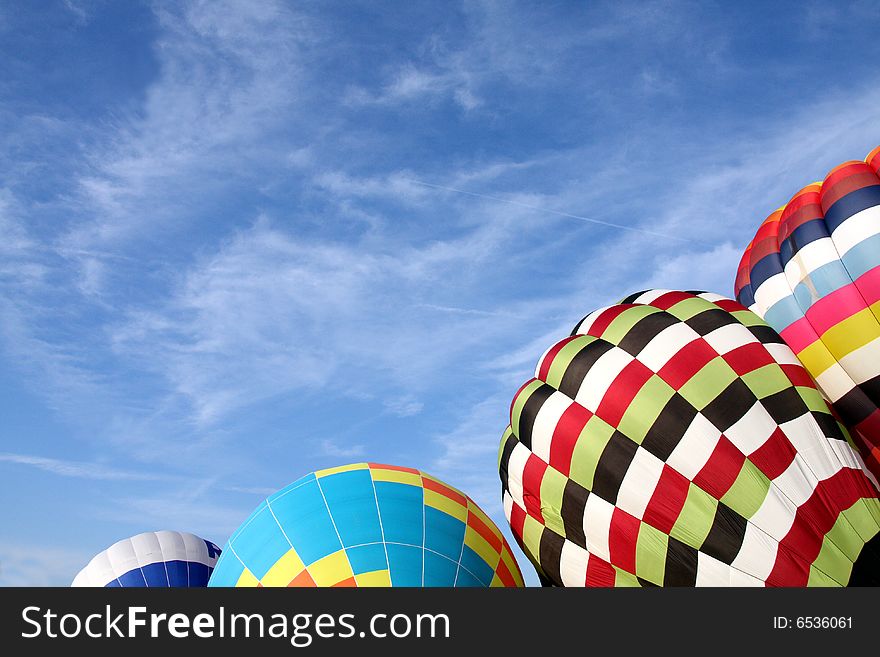 Multi-colored hot air balloons ready to ascend into the clear blue sky