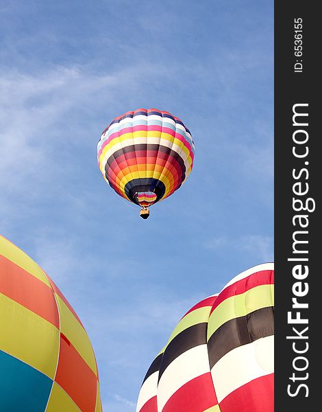 A multi-colored hot air balloon ascending into the clear blue sky