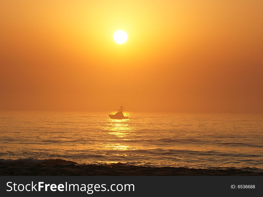 A small fishing boat runs in the glow of the morning sun along the Atlantic shoreline. A small fishing boat runs in the glow of the morning sun along the Atlantic shoreline.