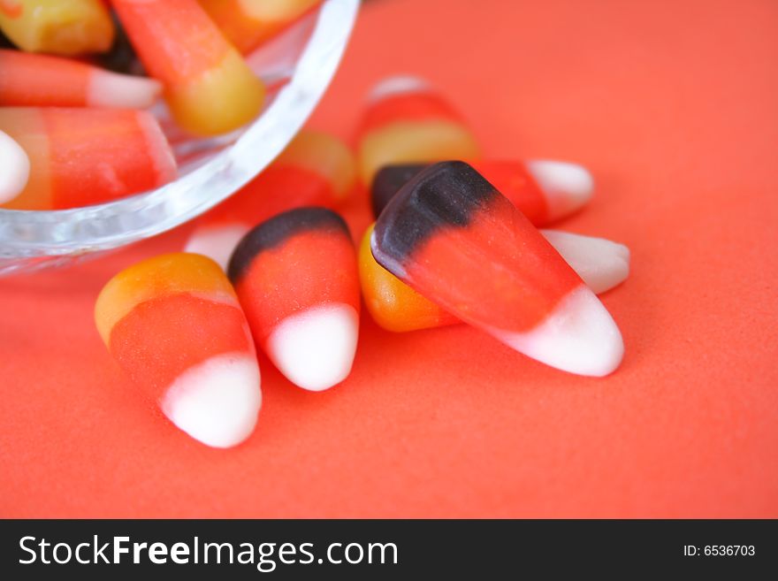 Close up of candy corn spilling out of a candy dish.