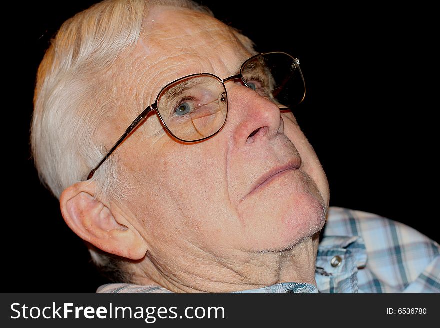 A head shot of a blue-eyed senior wearing glasses with a serious expression.  The background is black. A head shot of a blue-eyed senior wearing glasses with a serious expression.  The background is black.