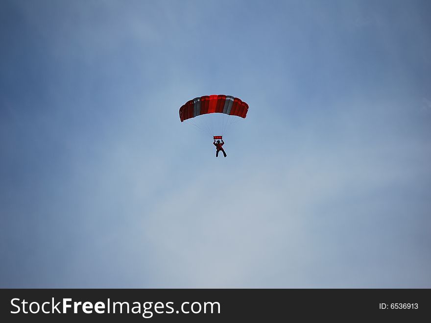 A Skydiver flying under a red canopy