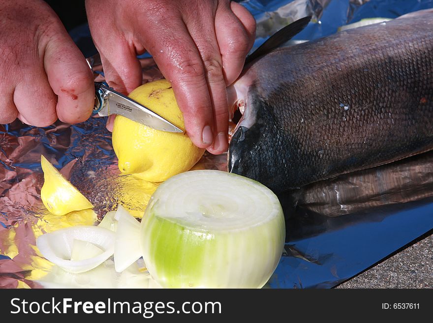 Cutting a lemon with onion and salmon are on the side. Cutting a lemon with onion and salmon are on the side