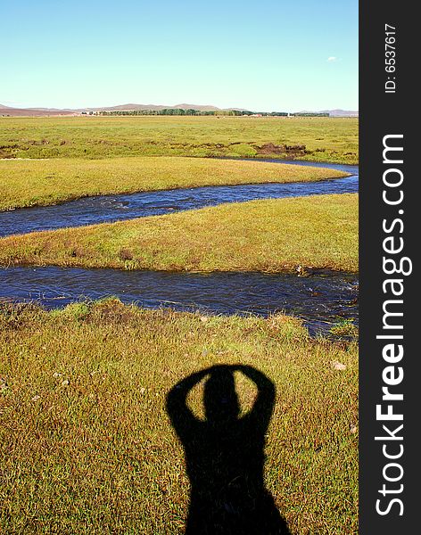 Photo of a person's imposing shadow upon grassland