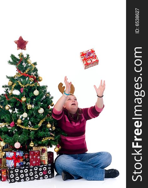 Happy girl catching a present by the Christmas tree on white background