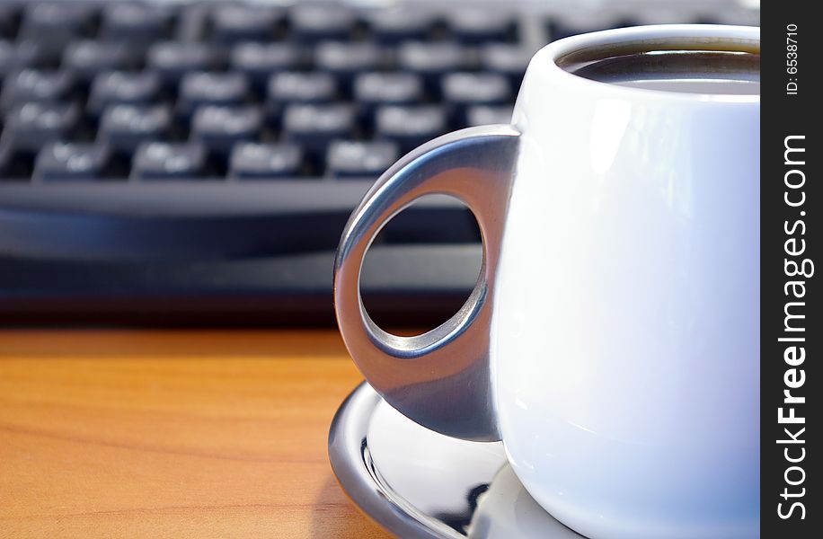 Cup of coffee and black keyboard on a table