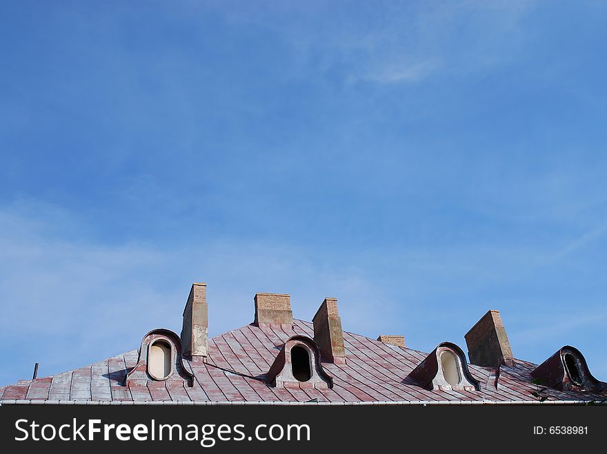 Old roof and chimney on the blue sky