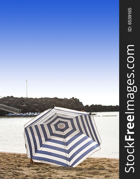 White and blue parasol on desert beach. White and blue parasol on desert beach