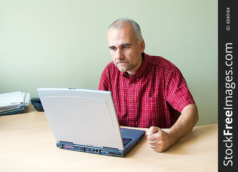 Angry office worker working at the desk with laptop and punching fist on the desk