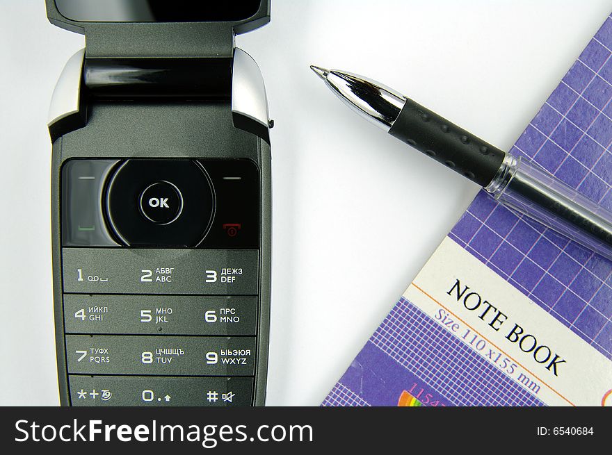 Mobile phone, pen and notebook on a white background.