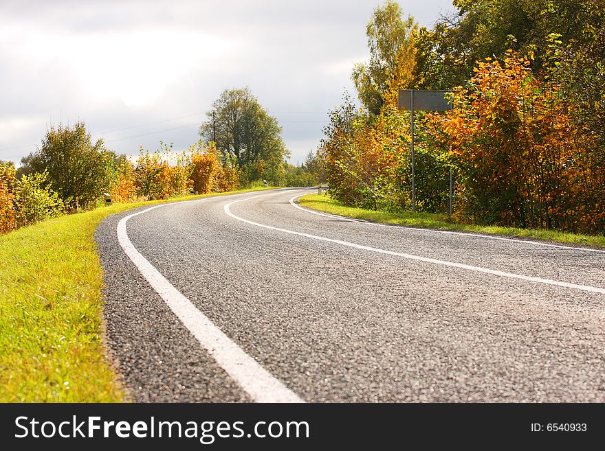 Autumn road. Green and yellow trees. Sun weather