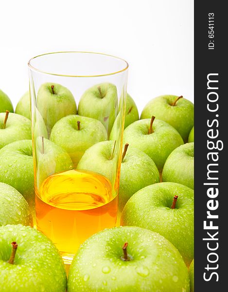 The glass with juice costs among set of green apples. The glass with juice costs among set of green apples