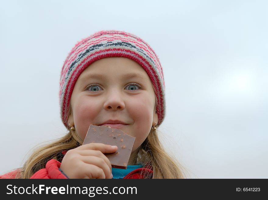 Young girl in a rose cap eats chocolate. Young girl in a rose cap eats chocolate