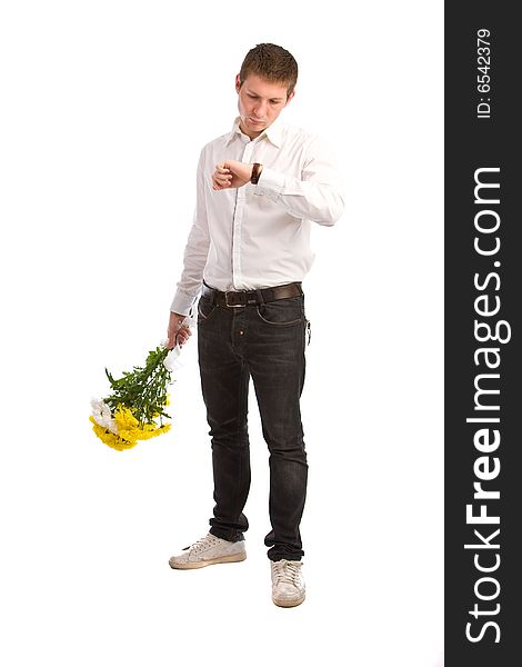 The men in a white shirt with a bouquet yellow flowers waits the girlfriend and looks at the watch. The men in a white shirt with a bouquet yellow flowers waits the girlfriend and looks at the watch