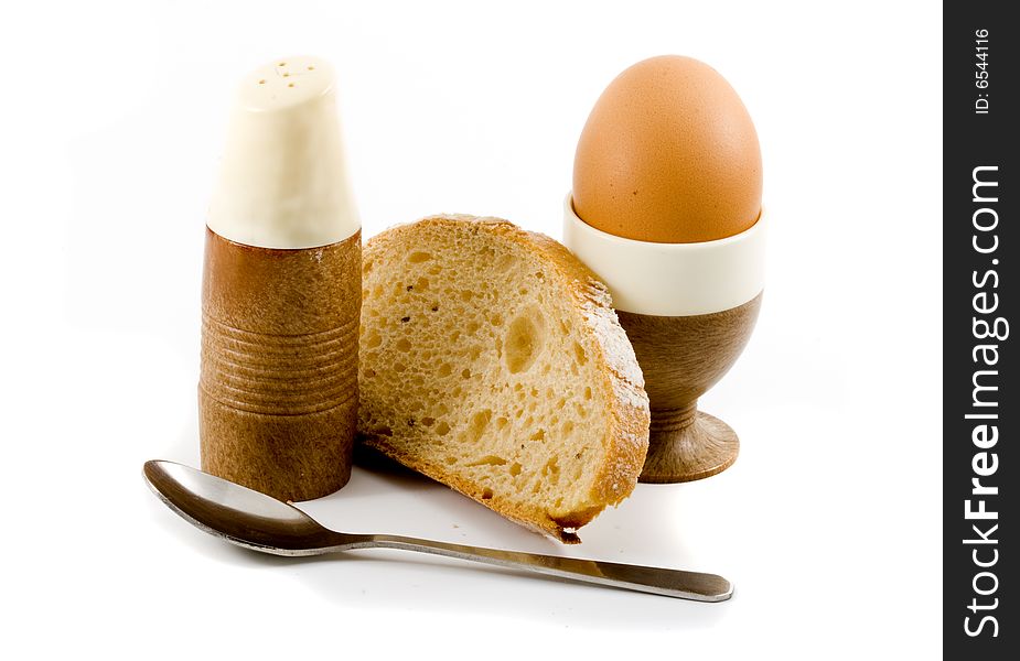 A soft boiled egg, a slice of bread and a saltpot