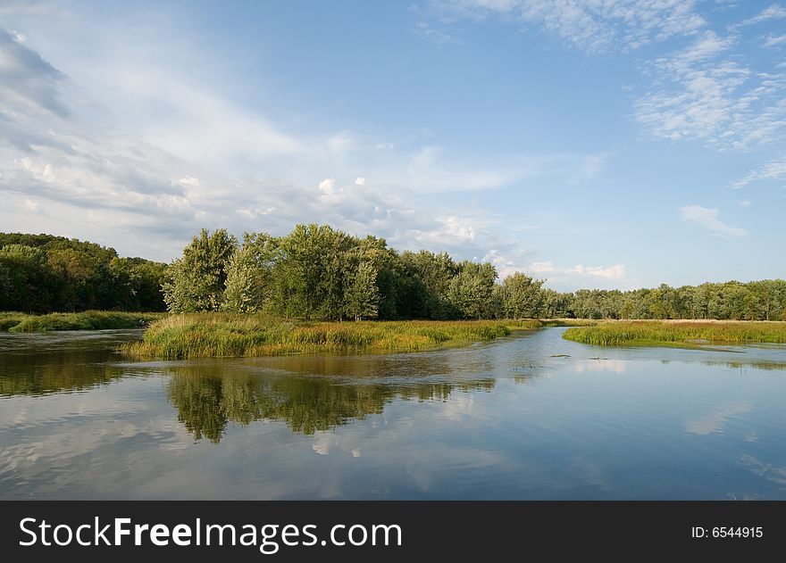 Trees and clouds reflecting off river landscape. Trees and clouds reflecting off river landscape