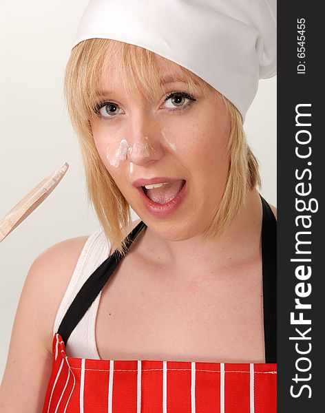 Attractive female chef in red apron with flour on her face. Attractive female chef in red apron with flour on her face